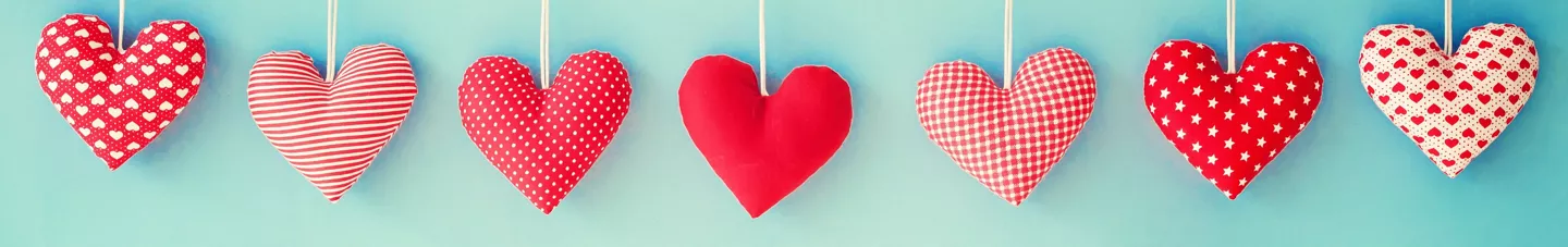 Corazones de tela rojos colgados sobre fondo azul como manualidades de San Valentín