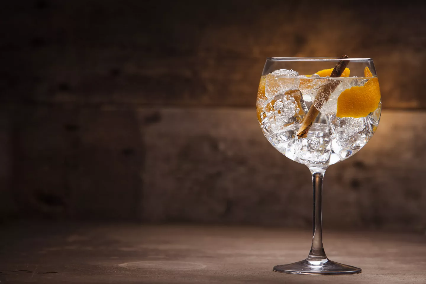 Gin-tonic navideño con canela en rama, hielo y piel de naranja en copa de balón