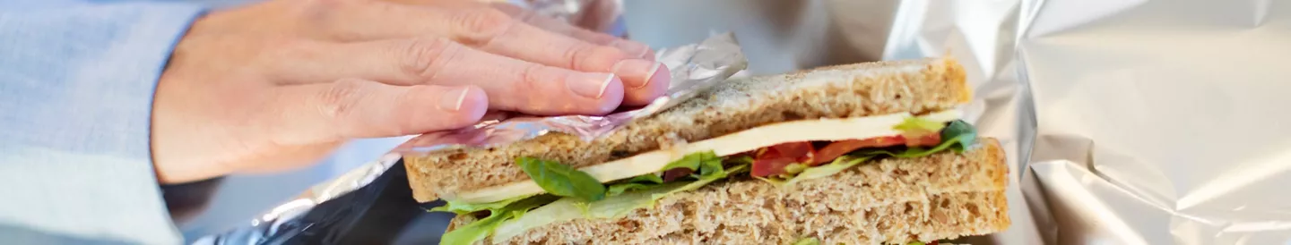 Persona envolviendo sándwich papel de aluminio