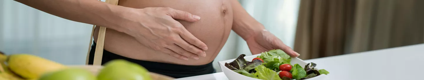 Mujer embarazada sosteniendo una ensalada como representación de la alimentación en el embarazo