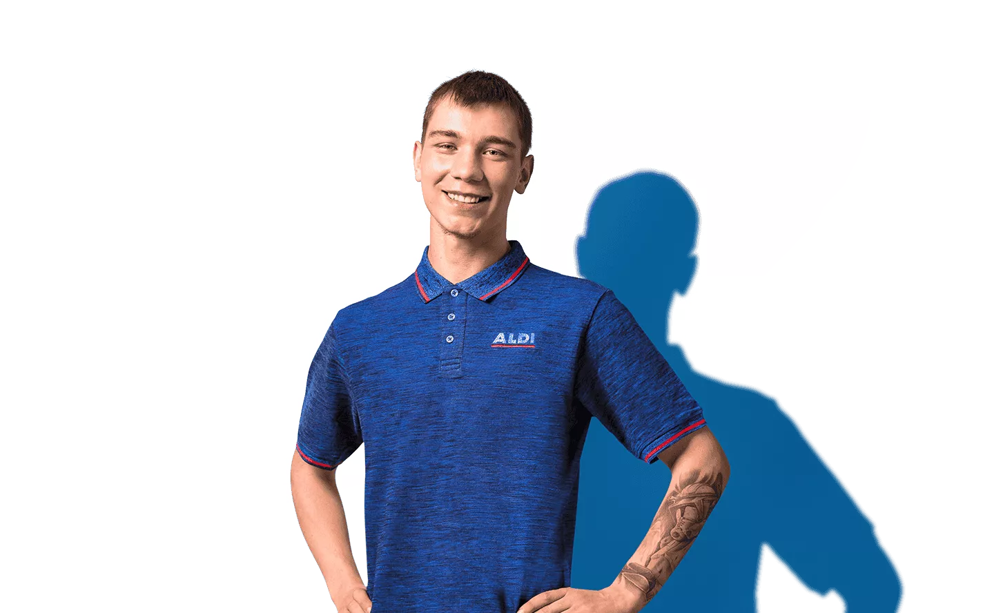  Ein lächelnder Mann schaut in die Kamera. Er trägt ein blaues Poloshirt und hat seine Hände in die Hüfte gestützt.