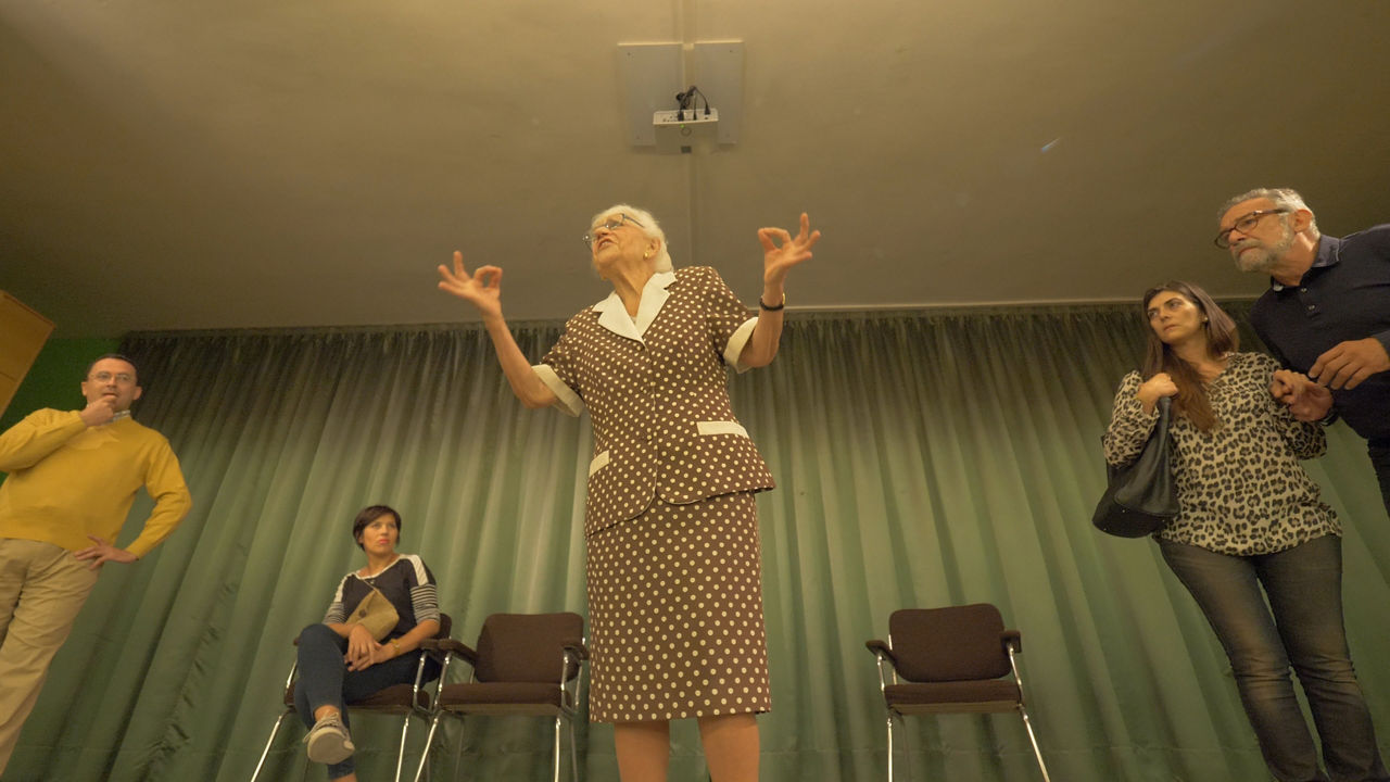Elderly woman speaking to small audience