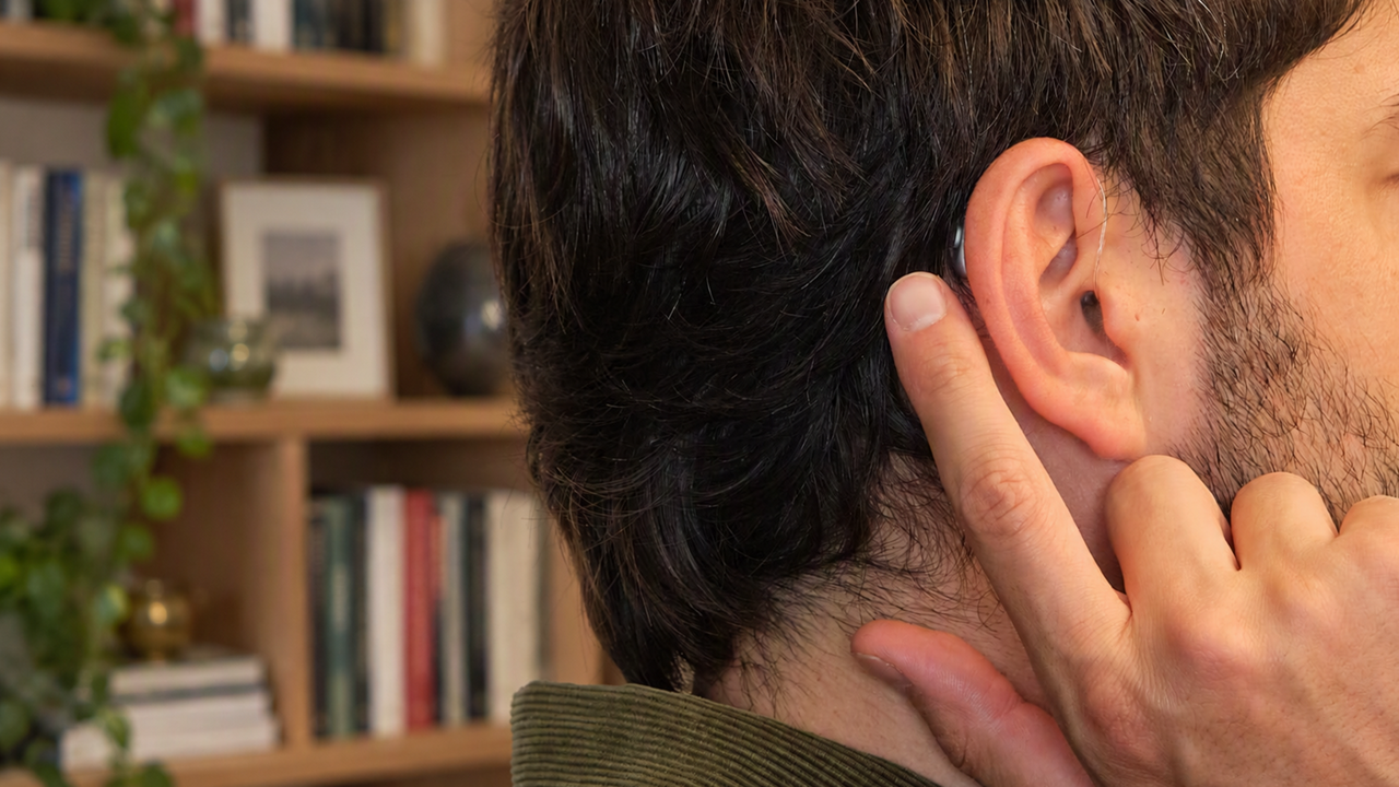 Man adjusting hearing aid at home
