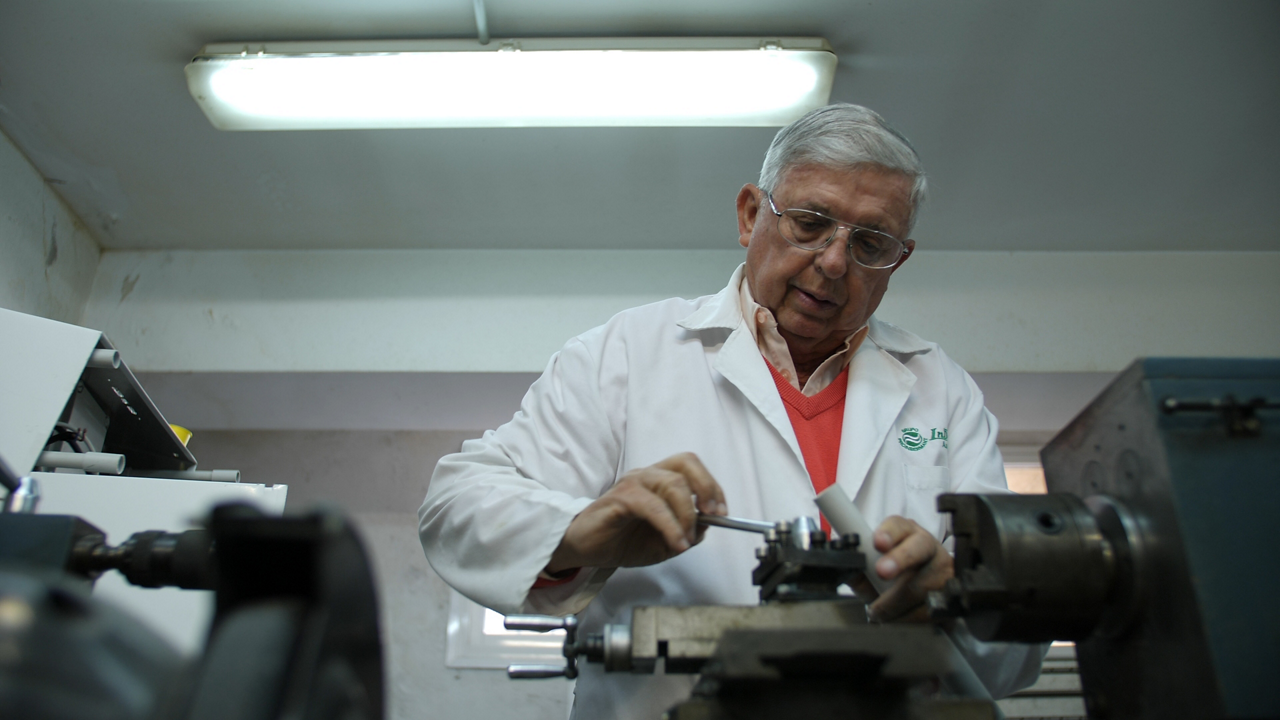 Senior technician operating metalworking machine in workshop
