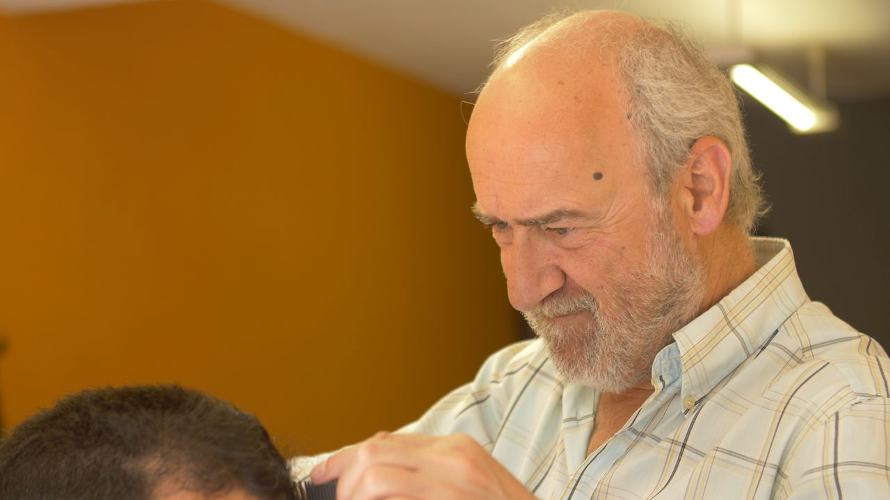 Senior barber carefully cutting client hair