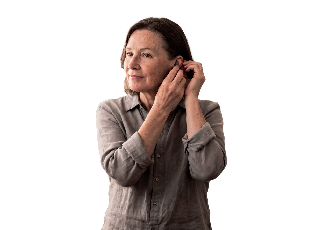 Mature woman adjusting hearing aid device