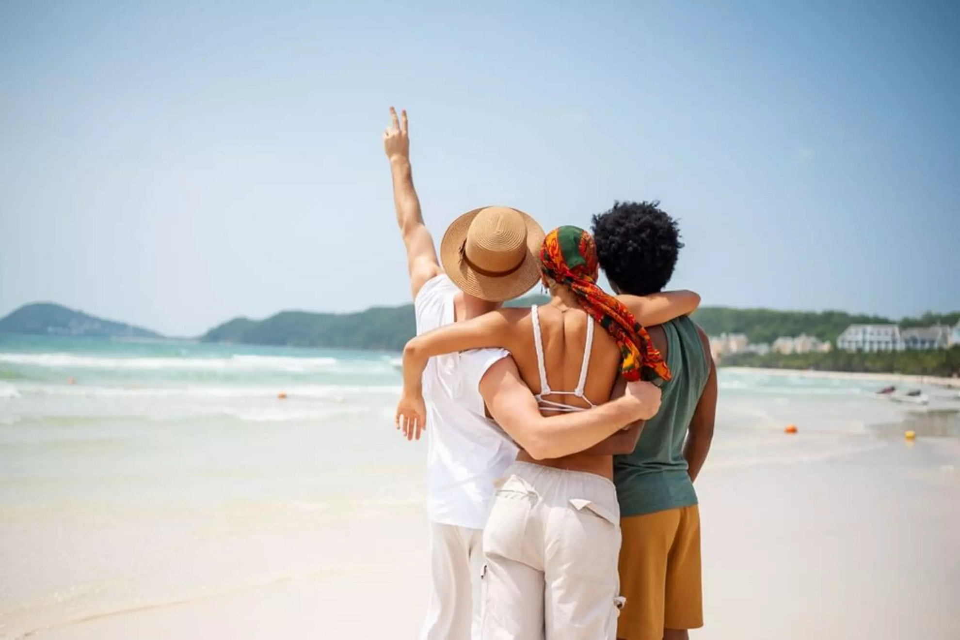 Three friends stand on a beach celebrating Mexican Valentine's Day.