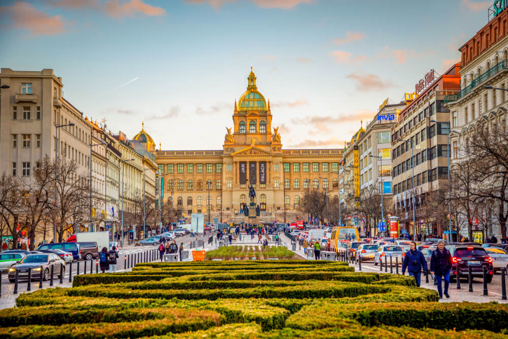 Museums in Prague: A big ornate building in a square with green shrubs in front of it