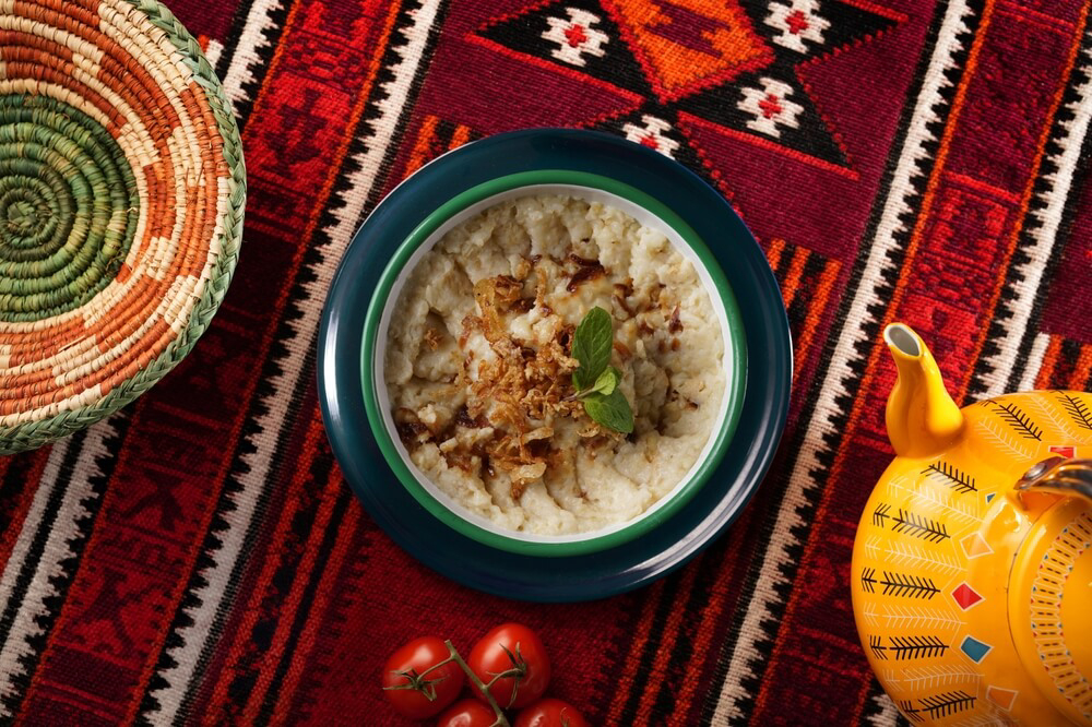 Arabische Küche: eine Schale mit Harees auf einer bunten Tischdecke.