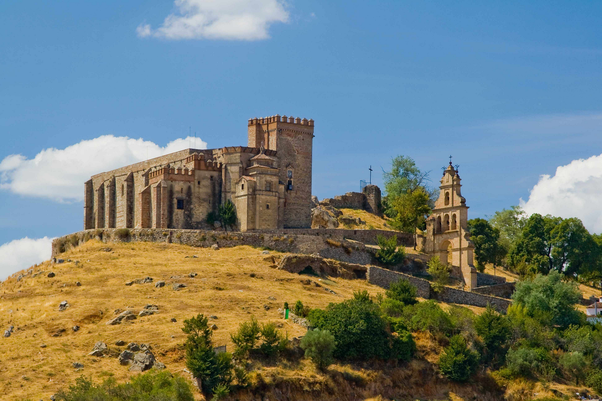 Burg von Aracena, Huelva, auf einem Hügel mit Kirchturm daneben.