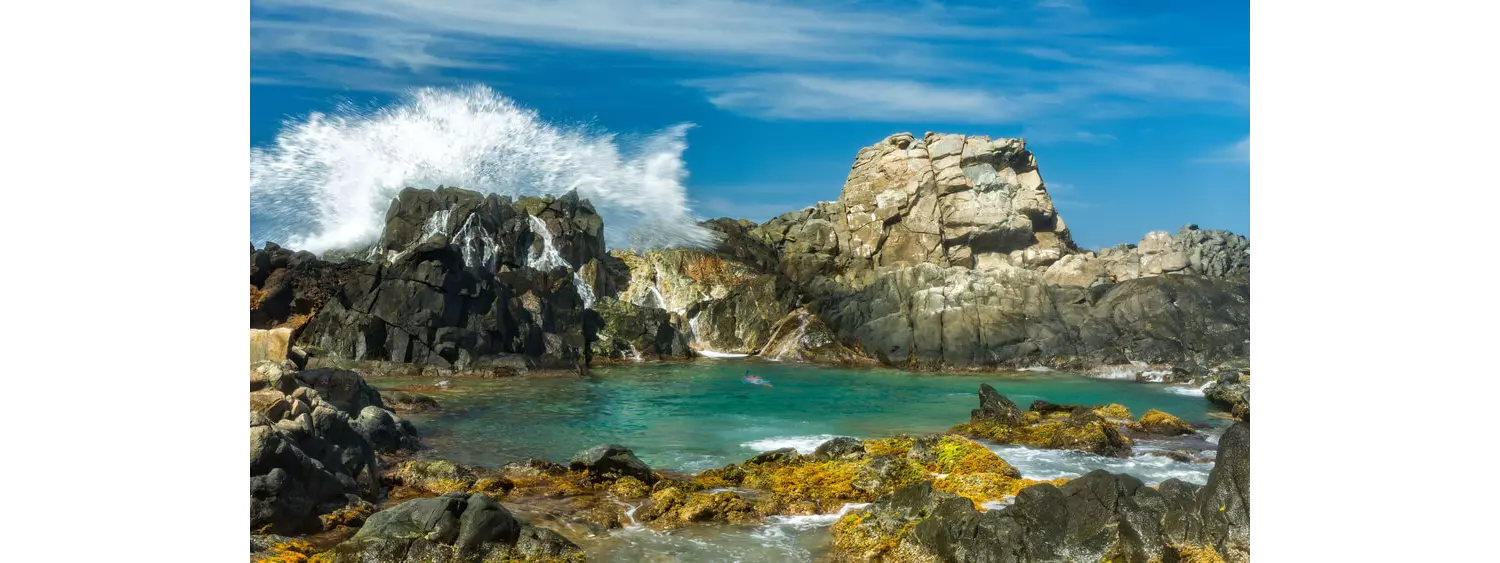 Conchi Natural Pool in Arikok National Park, surrounded by rugged rocks and crashing waves.