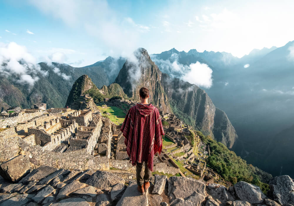 Mann im Poncho schaut auf die Ruinen von Machu Picchu