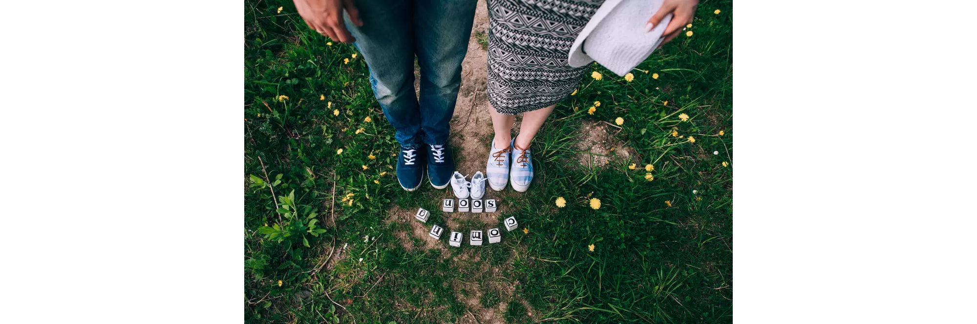 Babymoon: Füße von werdenden Eltern mit Babyschühchen und "coming soon"