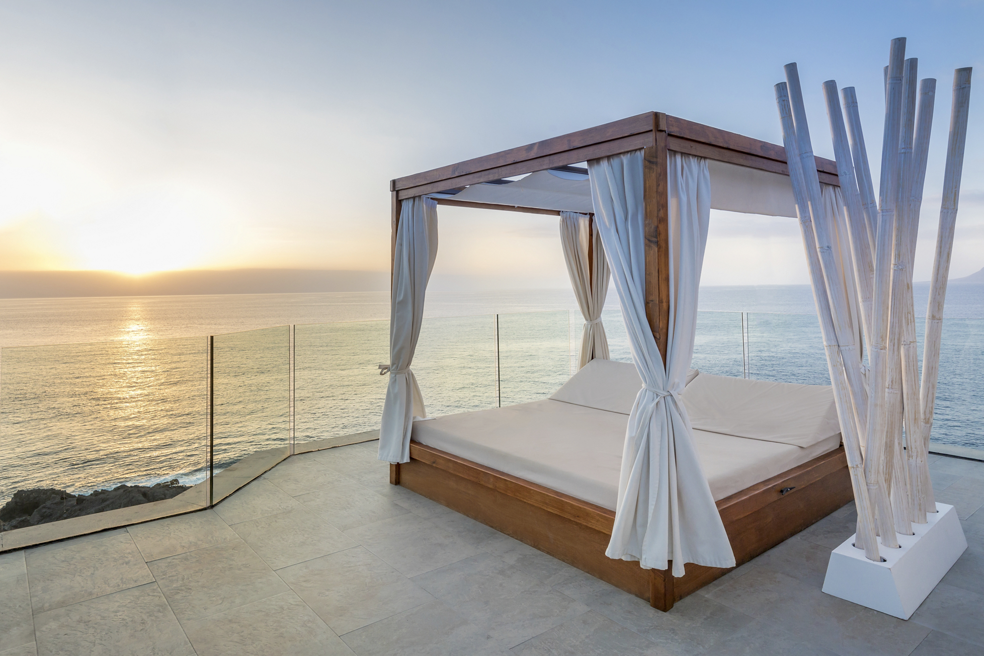 Babymoon-Urlaubsziele: balinesisches Bett auf hoch gelegener Terrasse mit Blick auf den Atlantik.