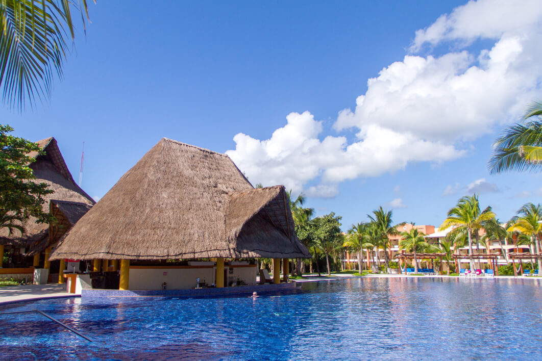 A swim-up bar sits amid palm trees at the Barceló Maya Colonial.
