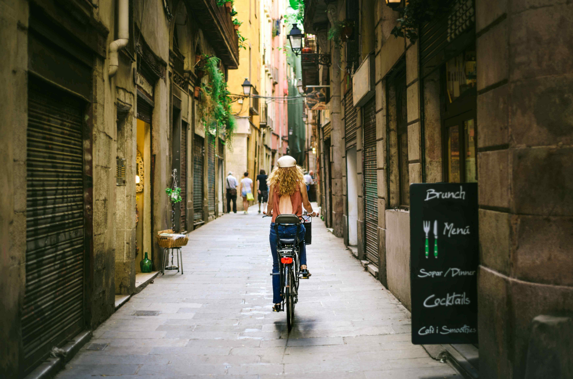 Frau auf dem Fahrrad in einer Gasse von Barcelona-Altstadt.