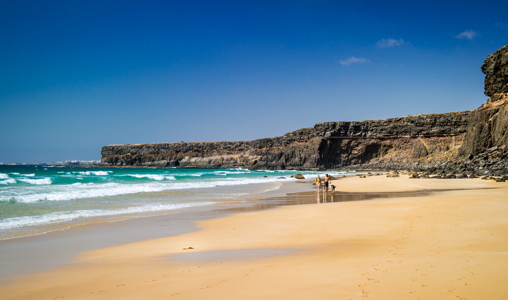 Playa del Aguila: Low-lying cliffs, golden sand and a family walking across the sand