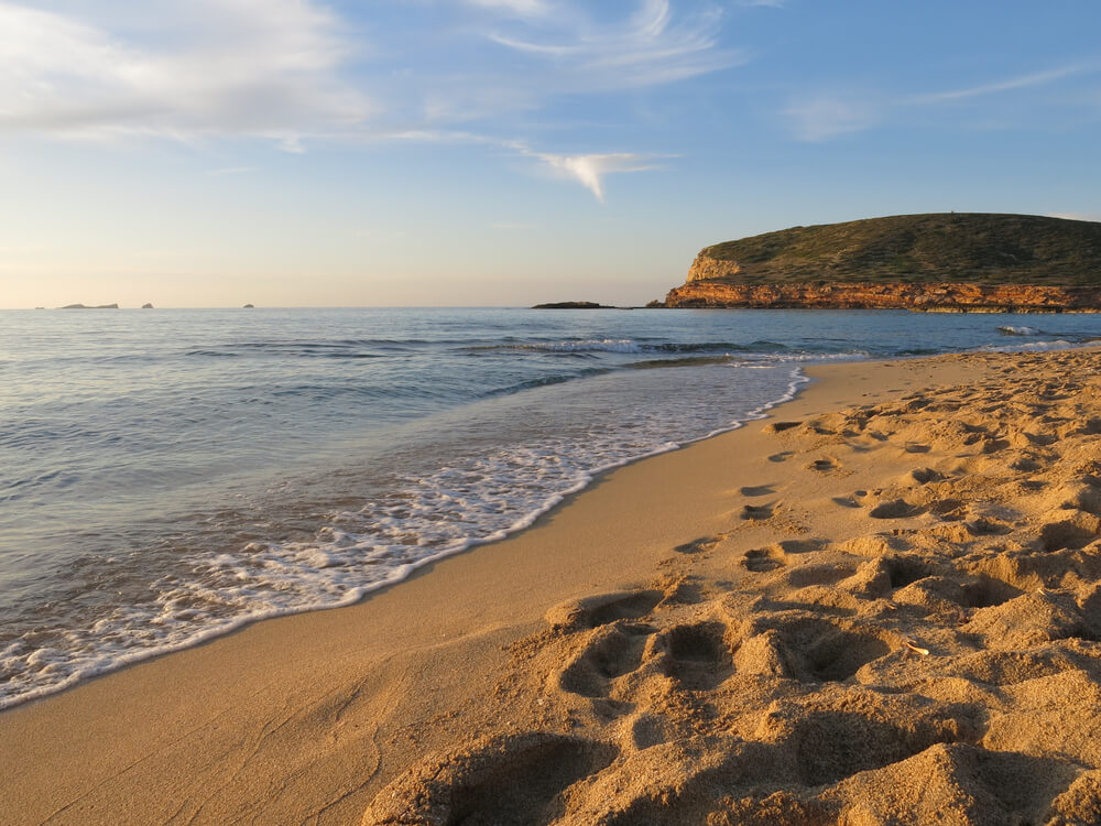 Best beaches in Ibiza: Sun setting over the golden sand beach of Cala Comte