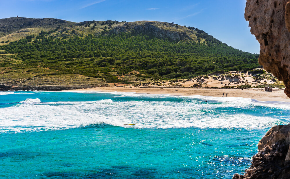 Cala Mesquida: Green hills with a golden beach and choppy seas