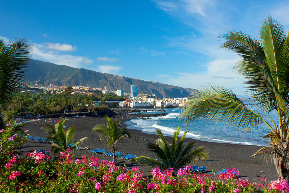 Best beaches in Puerto de la Cruz: Playa Jardín with blue loungers and the city in the background