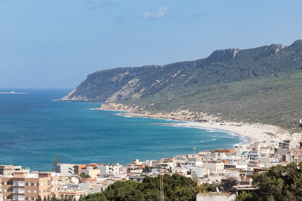 Rafraf beach: a coastline backed by green hills and cliffs with a town in the foreground