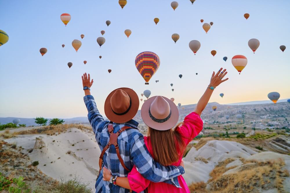 Cappadocia: A couple looking out over the hot air balloons in Cappadocia, Turkey