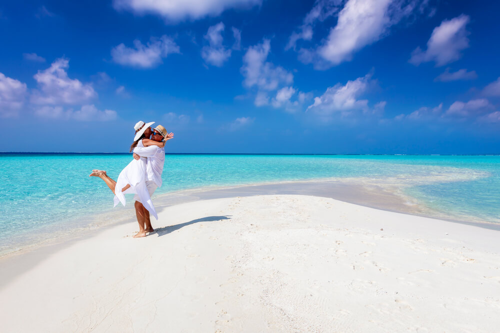 Maldives: A couple embracing on a white sand beach in the Maldives