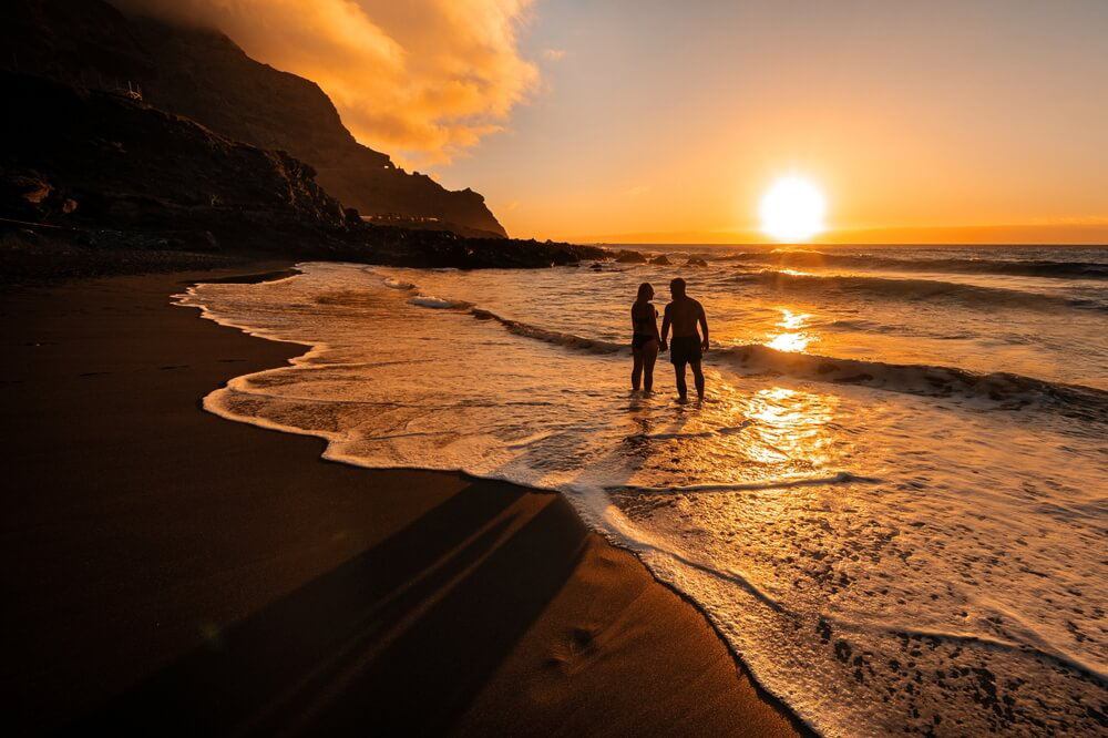 Tenerife: A couple walking along the shoreline at sunset