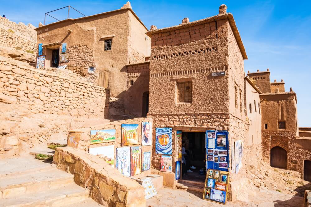 Aït Ben Haddou: A golden red mud house with paintings for sale outside
