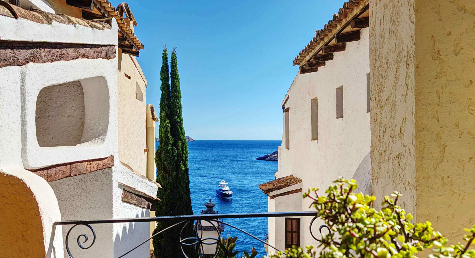 Best summer holiday destinations: The blue sea seen through a white Spanish wall