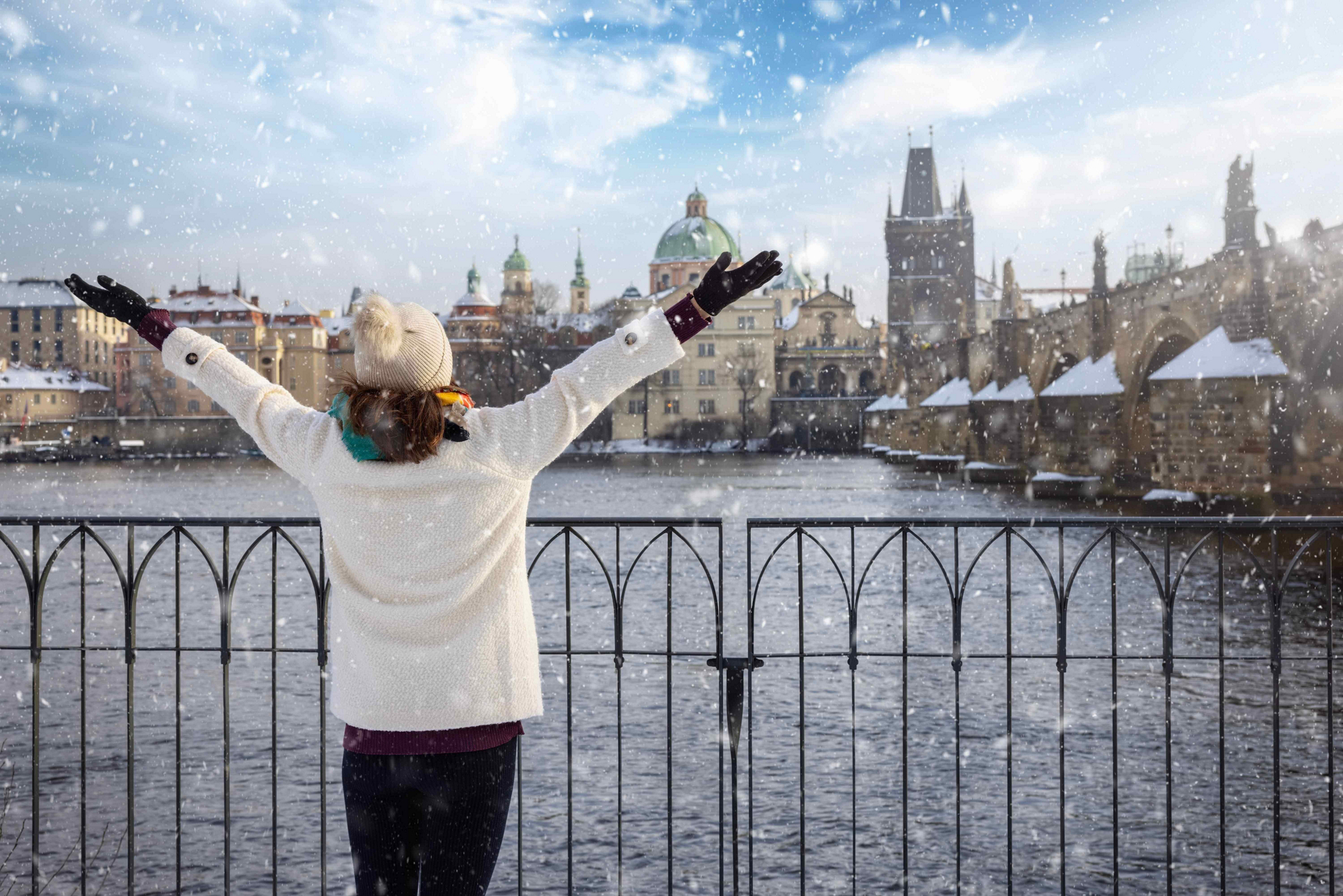 Best winter city breaks in Europe: A girl, arms outstretched overlooking a view of snowy Prague