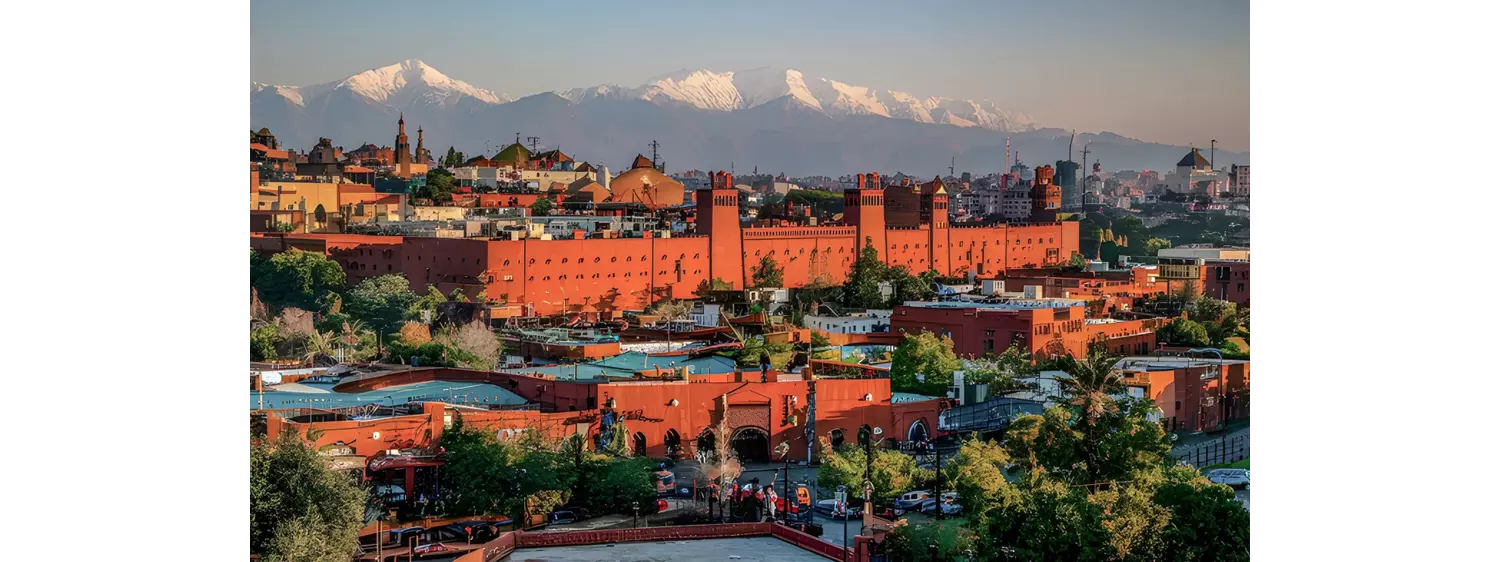 Marrakech: A large red building in the city with mountains in the background