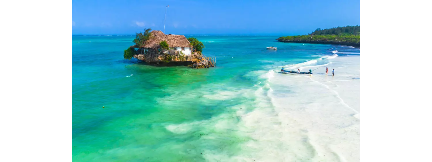 White sand and topaz sea with a rock in the middle and a house on top
