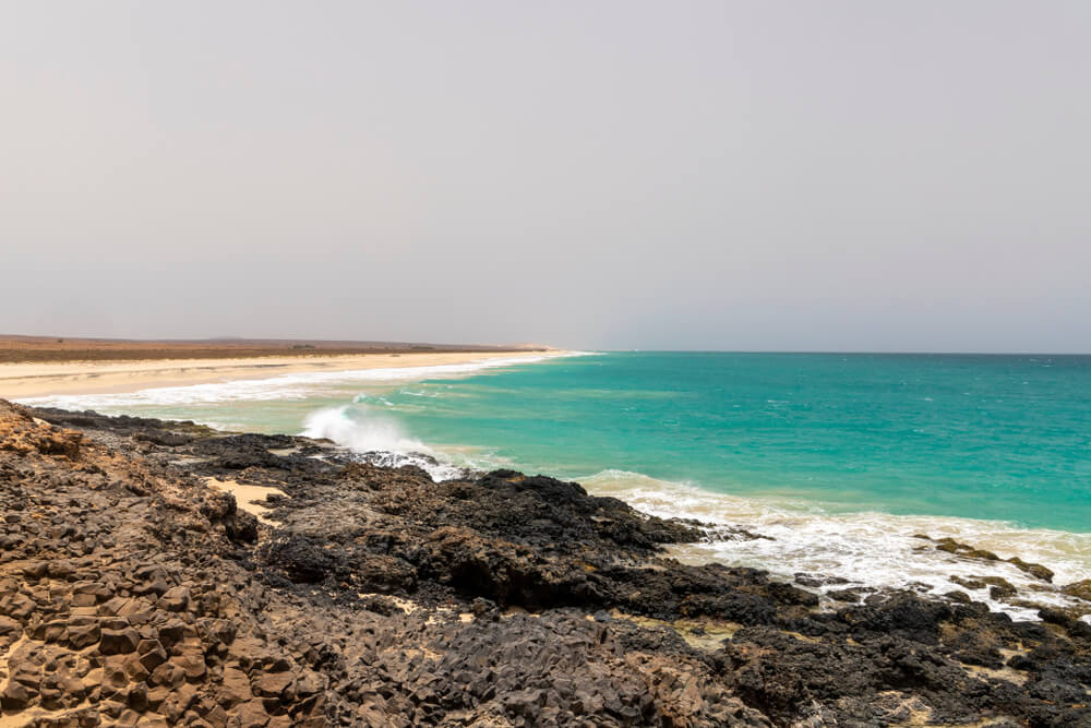 Ervatao Beach Cape Verde: Volcanic rocks framing a golden coastline and gentle sea