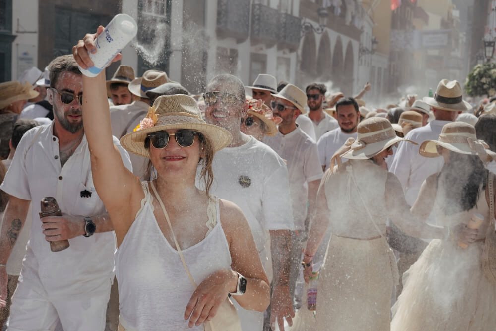 Los Indianos: A group of people dressed in white, throwing talc