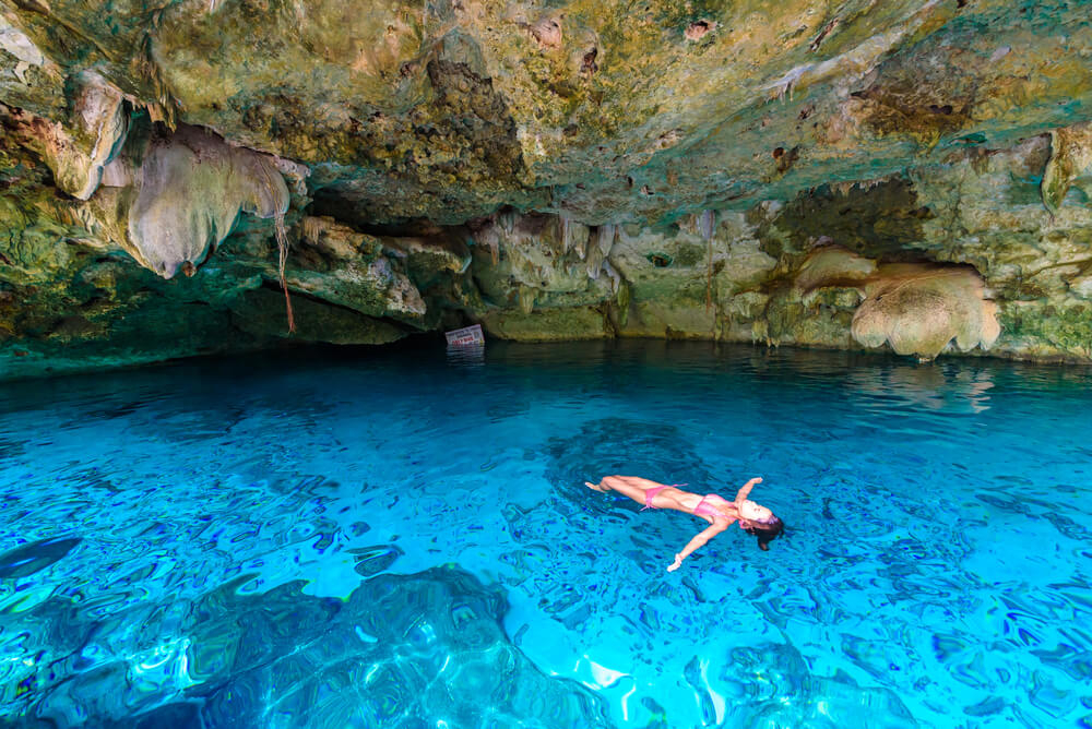 Frau badet im blauen Wasser des Cenote Dos Ojos.