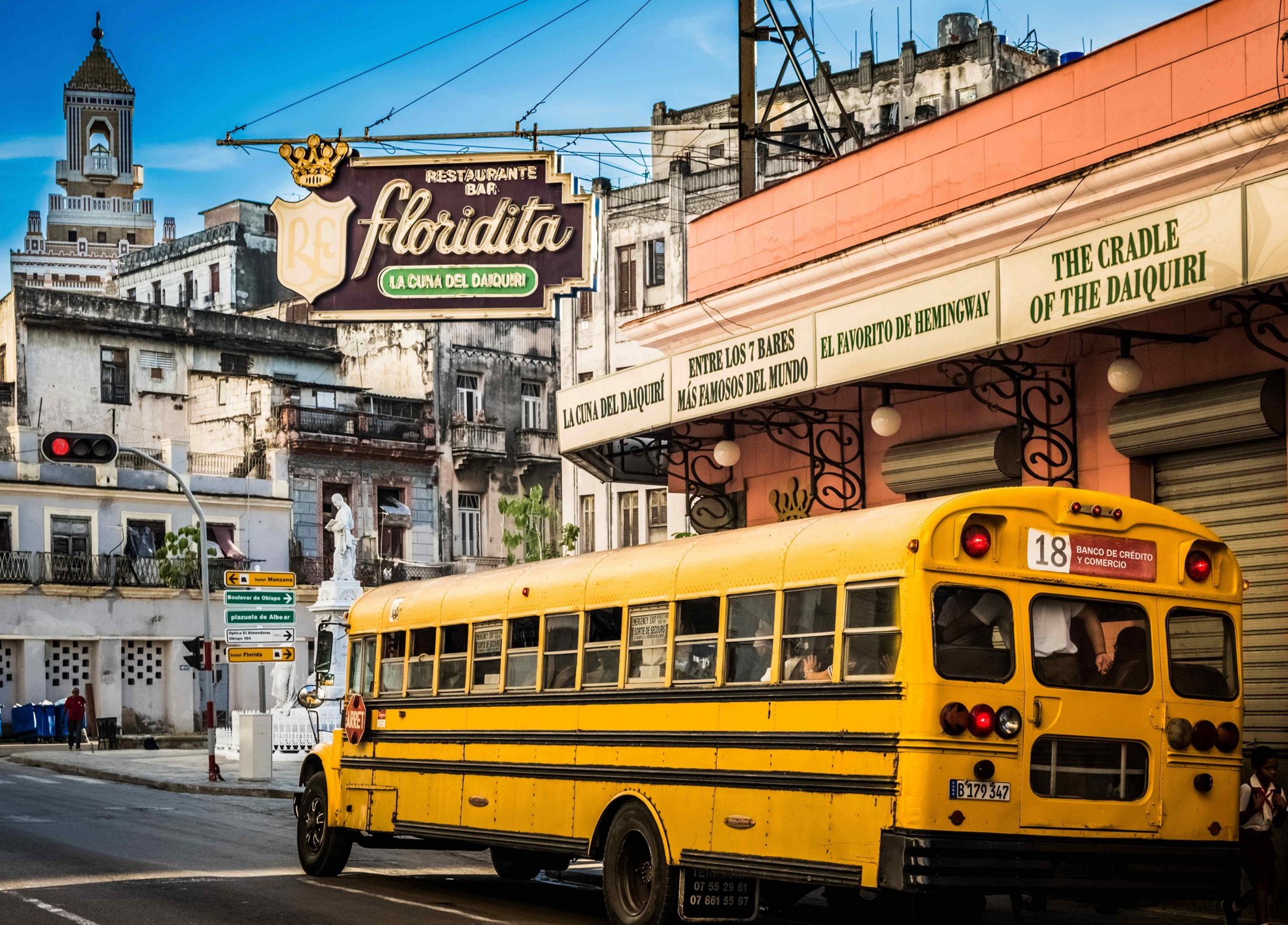 El Floridita: A pink bar on the street corner of a busy street with a red old car