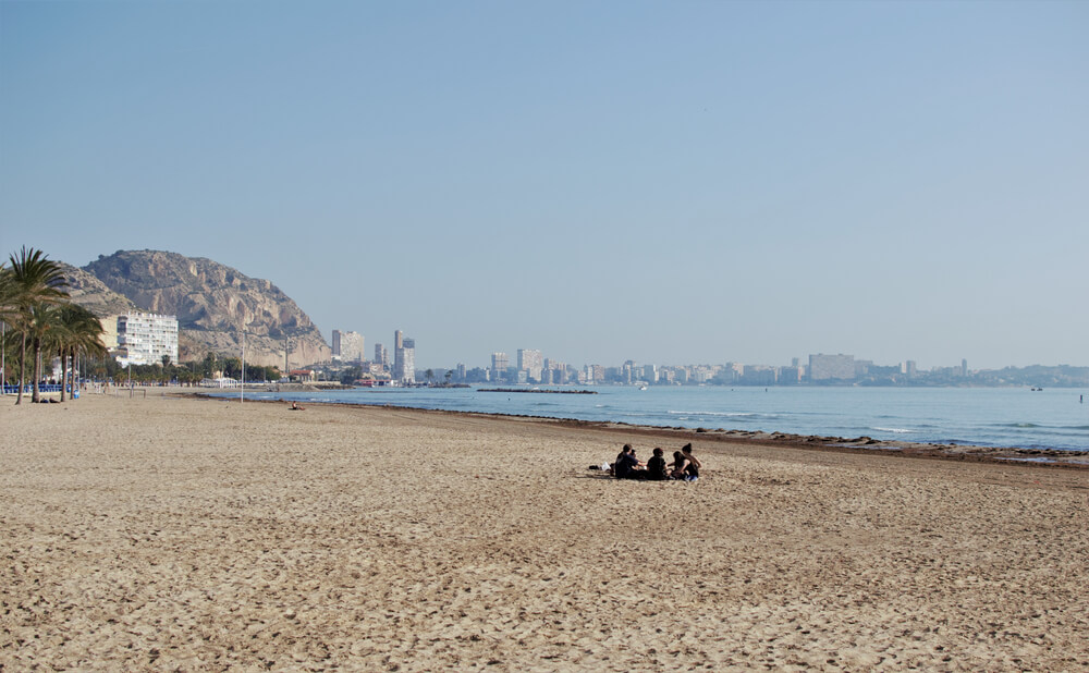 Costa Blanca Best Beaches: Large white beach with people sitting on the sand