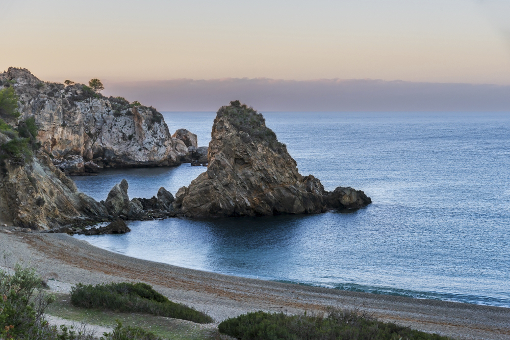 Maro: Sun setting over white sand beach and cliffs