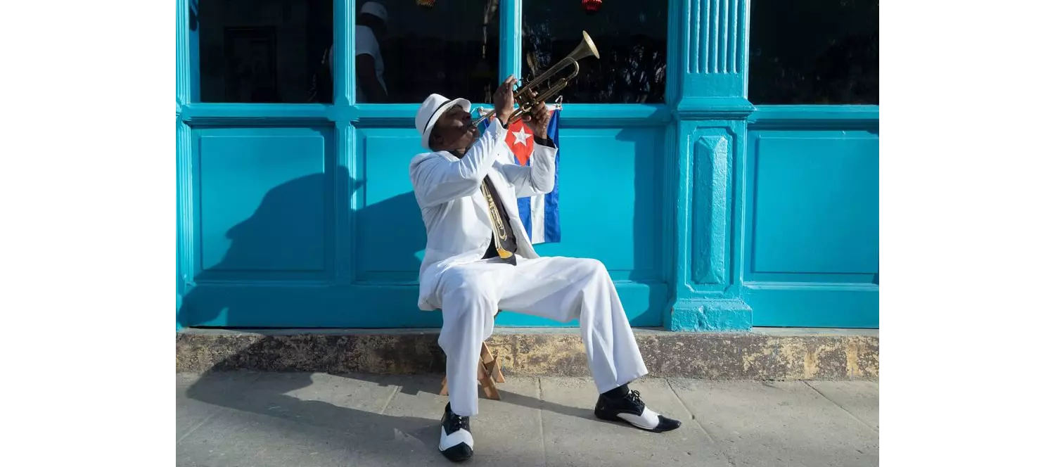 Cuban Culture: A man sitting on the sidewalk playing a trumpet
