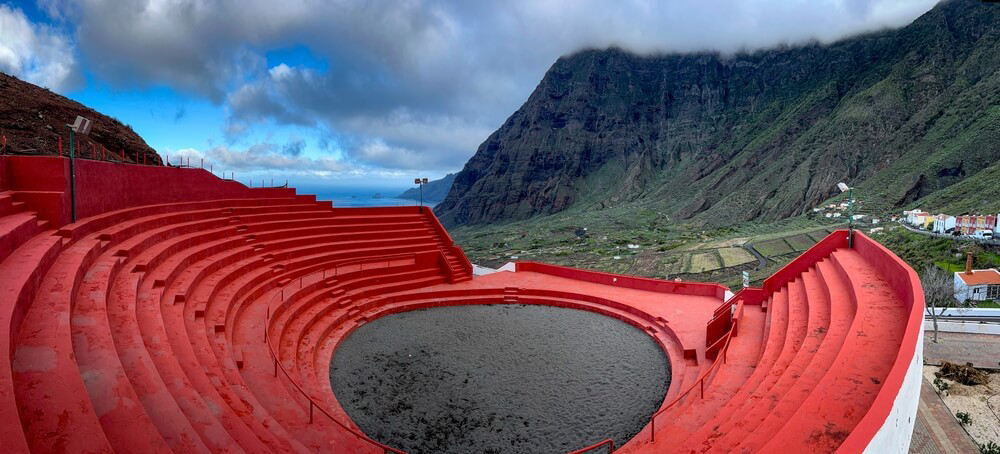 Lucha Canaria: A red painted circular stadium with mountain views
