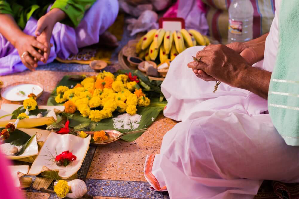 Indian Day of the Dead: Women seated on the floor surrounded by marigolds and plates