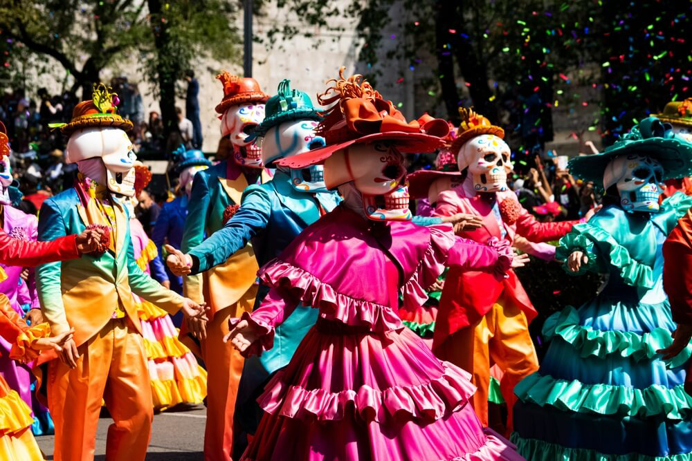 Mexican Day of the Dead costumes are pictured in a colorful parade.