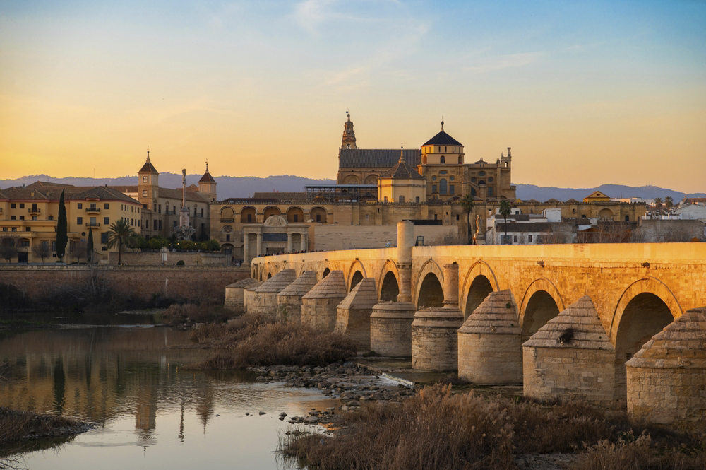 Córdoba: A sunset view of the Roman bridge and the Mesquita in the distance