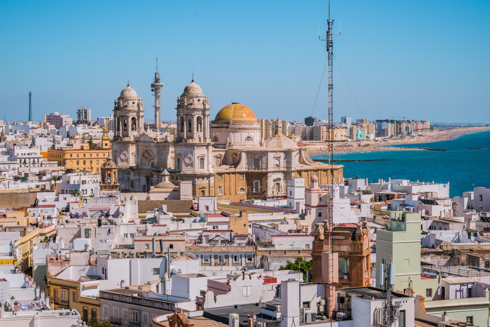 Die besten Reiseziele 2026: Kathedrale von Cádiz mit dem Strand der Neustadt im Hintergrund.