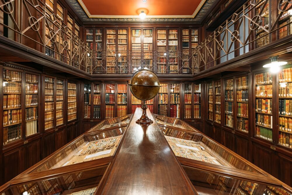 Galerien mit Bücherschränken und ein Globus auf einem Tisch in der Arús-Bibliothek, Barcelona.