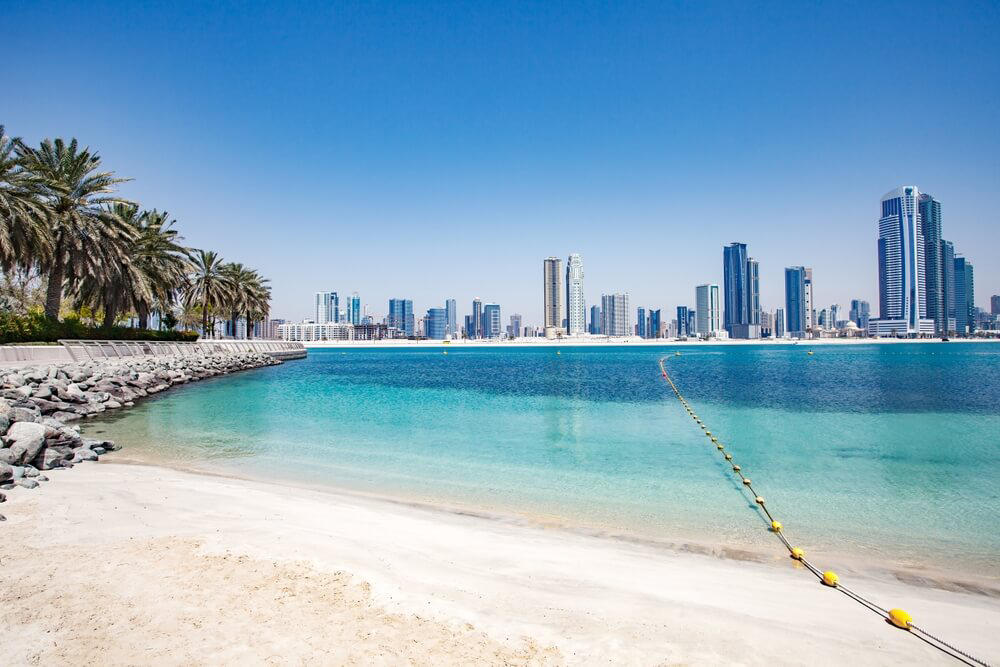 Al Mamzar Beach: White sand, blue water surrounded by palm trees and skyscrapers