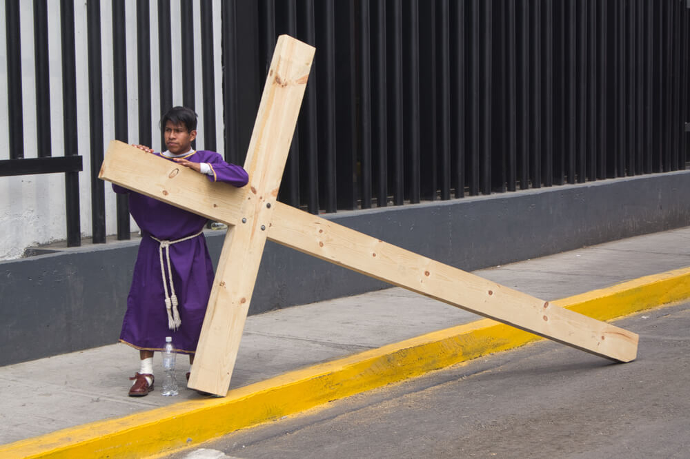 Easter in Mexico: A man holds onto a large cross as he waits for the start of the Passion Play