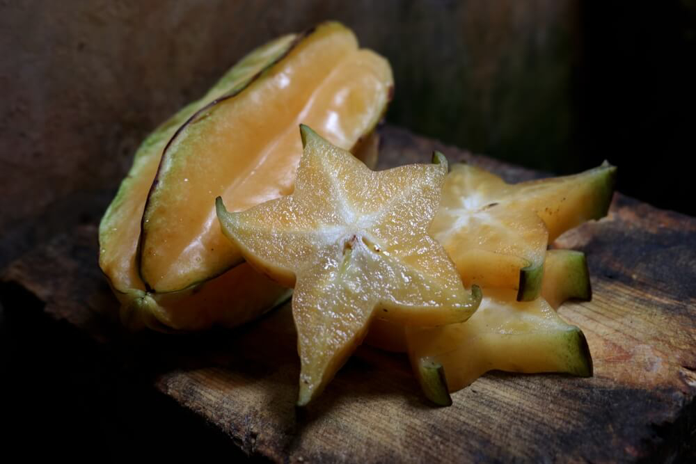 Exotic Fruits: A star fruit, carambola, sliced on a wooden surface