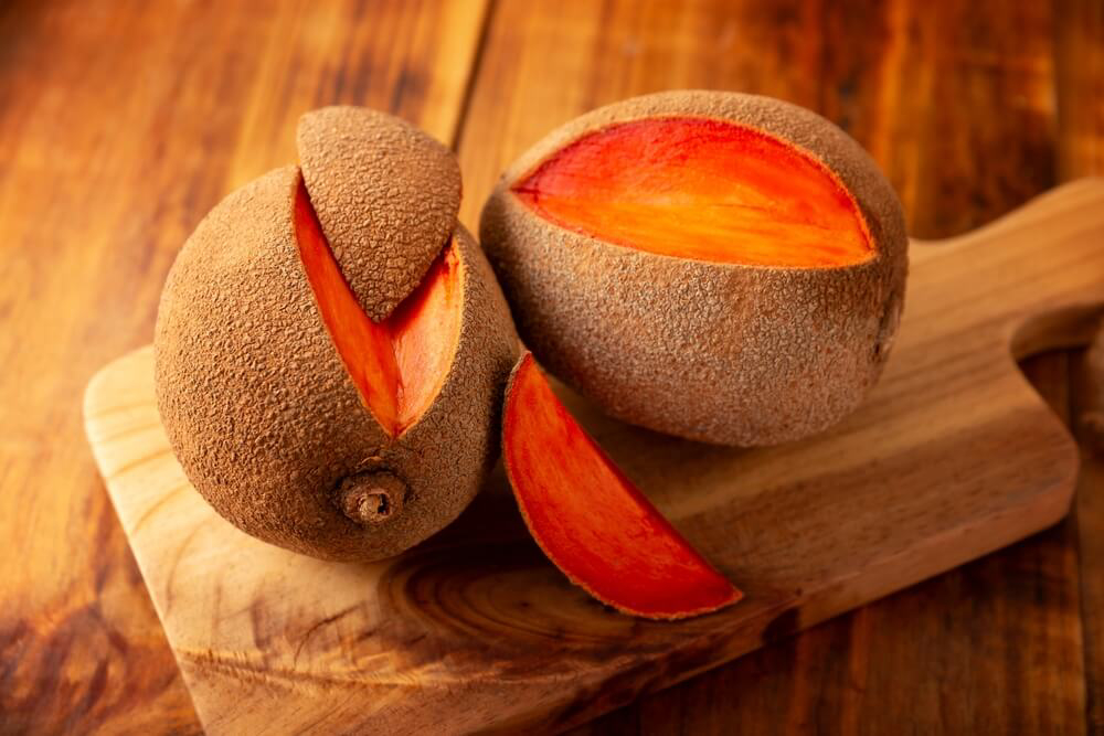 Mamey Apple: A wooden board with two sliced open mamey apples on top